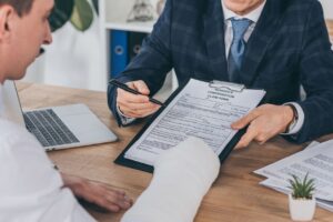 hombre firmando un formulario de reclamación de daños con un abogado