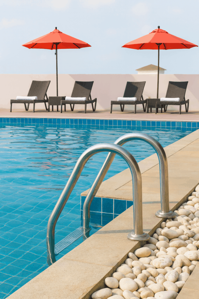 What are the liability laws for swimming pool injuries shown with a rooftop pool, stainless steel ladder, and sun loungers under umbrellas.